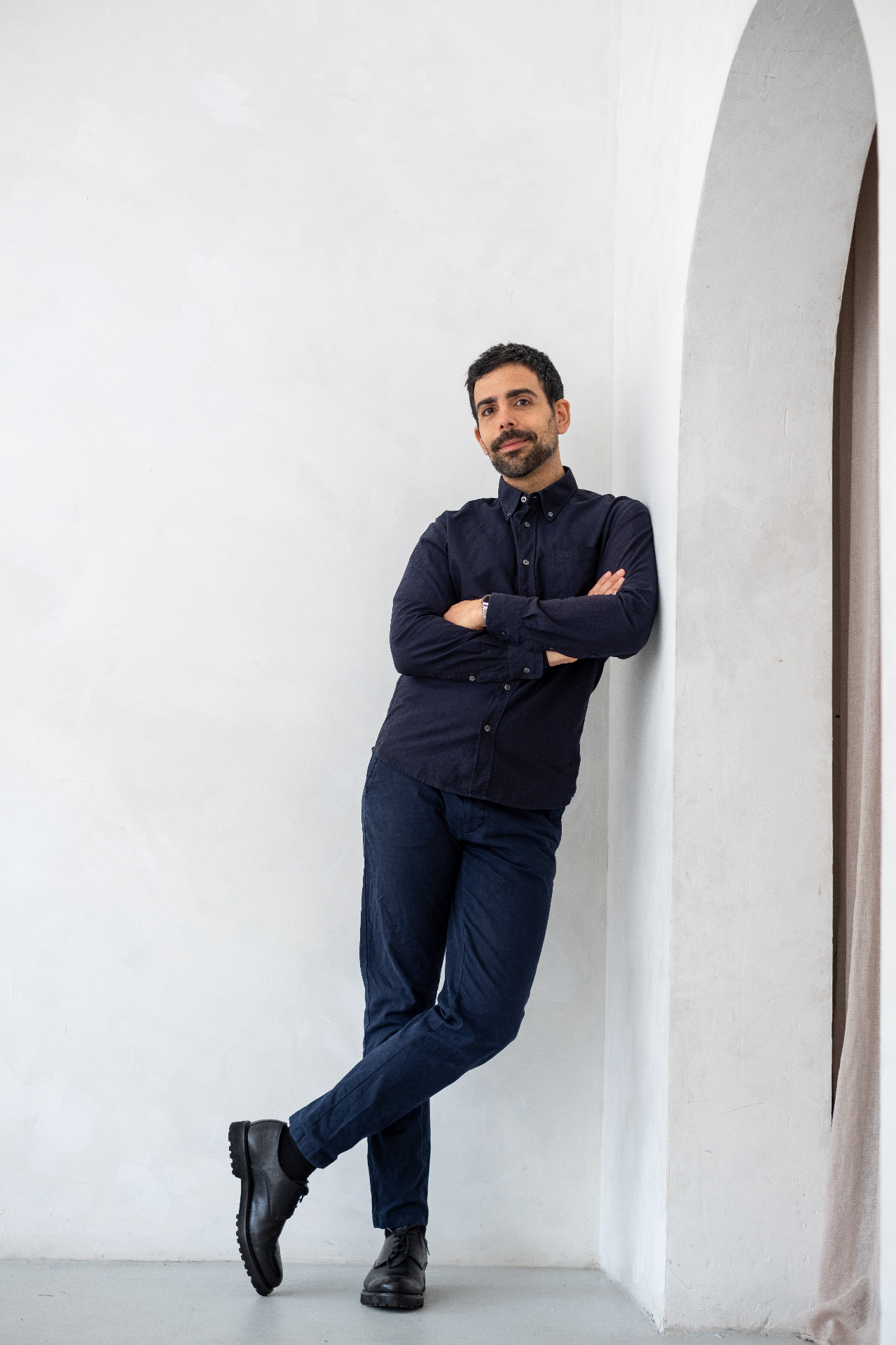 Giuseppe, dating coach for professional men in London, leaning against a white wall